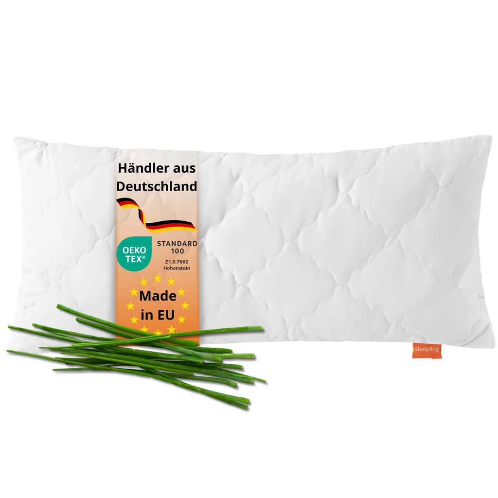 A white quilted pillow is shown on a white background with a tag and some chives.