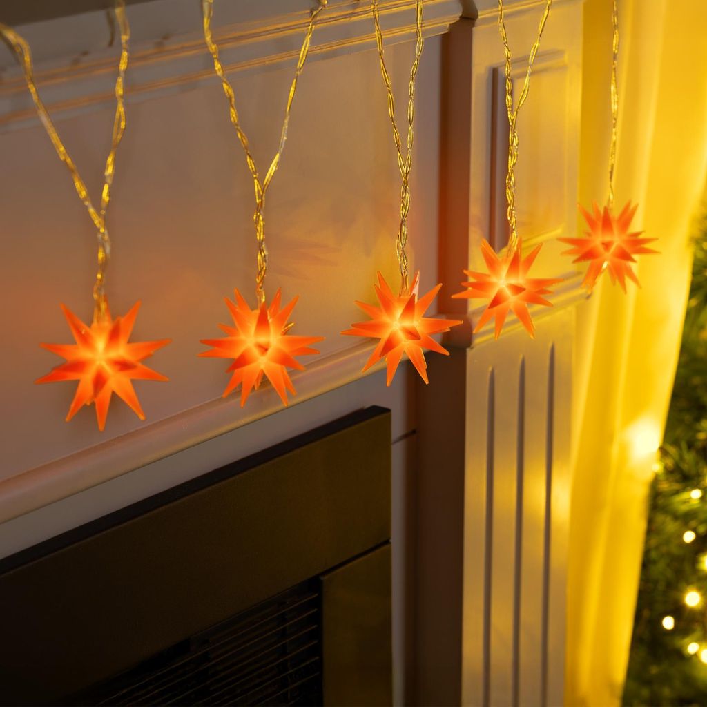 A string of orange star-shaped LED lights draped over a fireplace mantel.