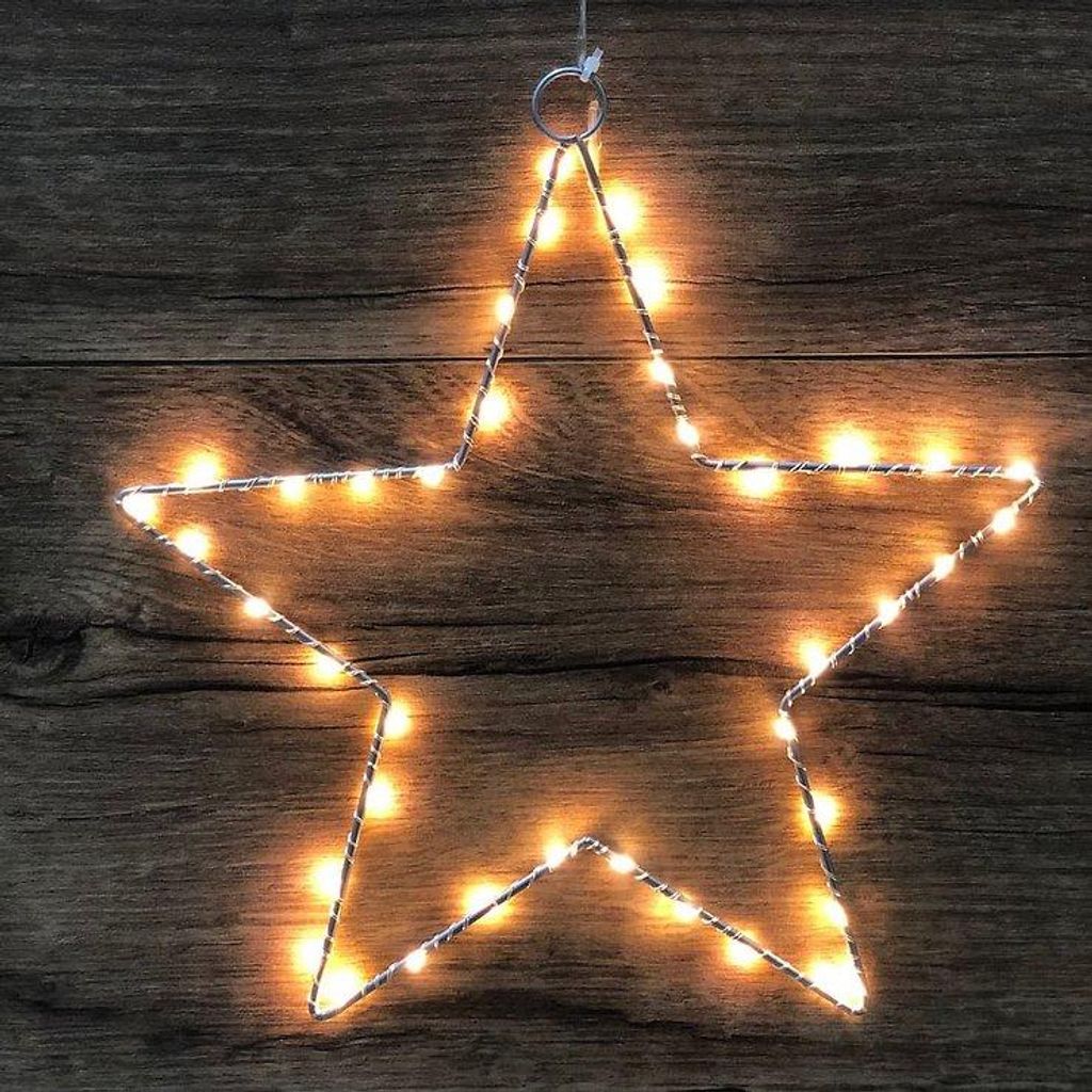 A star-shaped LED light decoration hanging against a wooden background.
