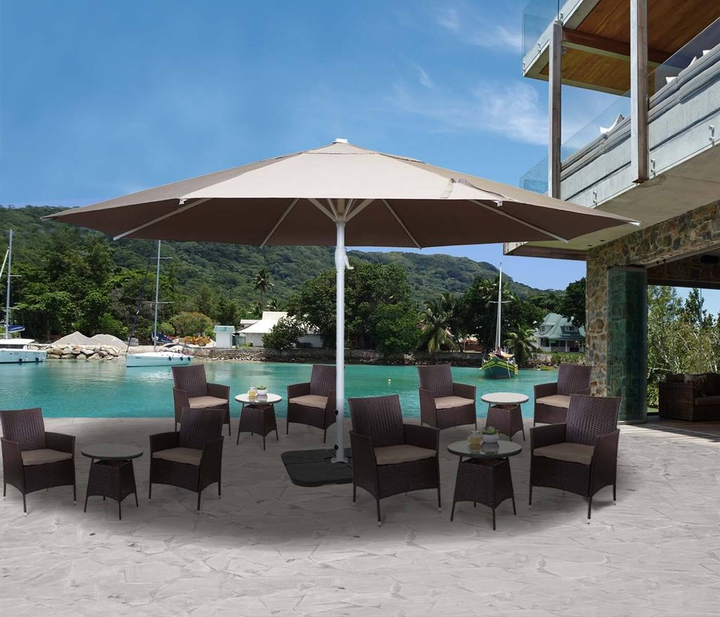 An outdoor patio scene with a large umbrella and seating area overlooking a body of water with boats and a building.