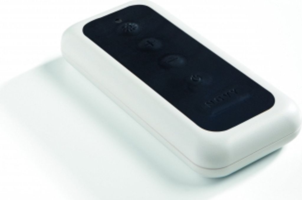 A white remote control with a black panel and buttons, placed on a white surface with a shadow.