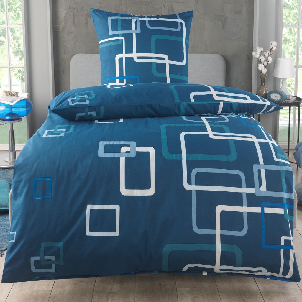 A neatly made bed with blue bedding featuring a geometric pattern.