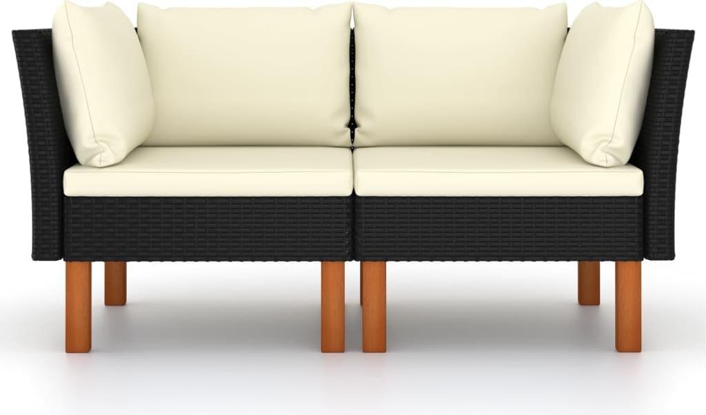 A studio shot of a black rattan sofa with cream cushions.