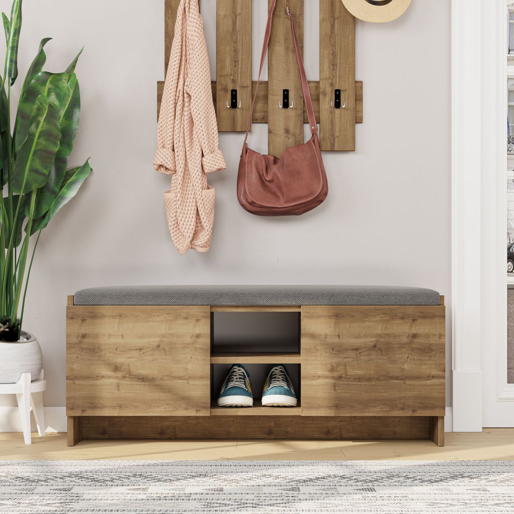 An entryway bench with storage, a coat rack with hanging items, and a plant.