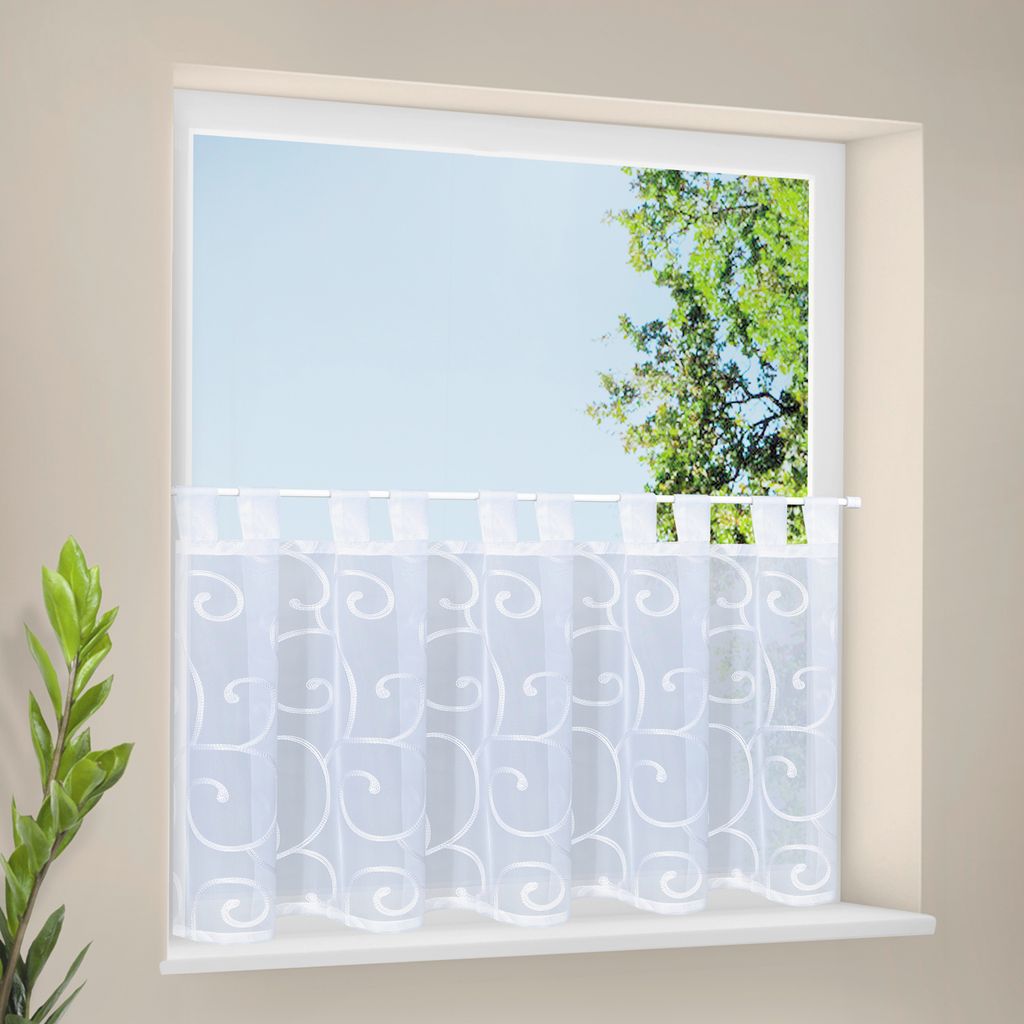 A white sheer curtain with a swirl pattern hangs across a window.