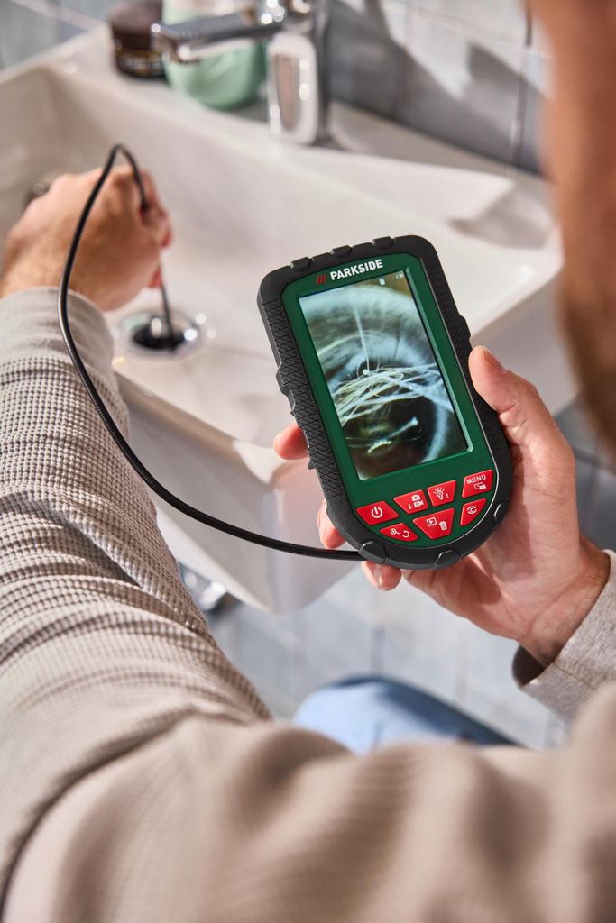 A person is using a digital inspection camera to look into a sink drain.