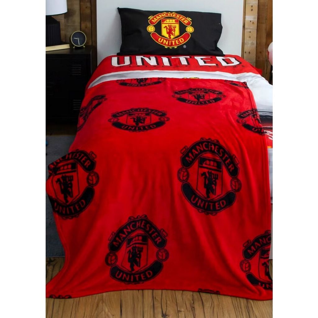 A bed with Manchester United themed bedding.
