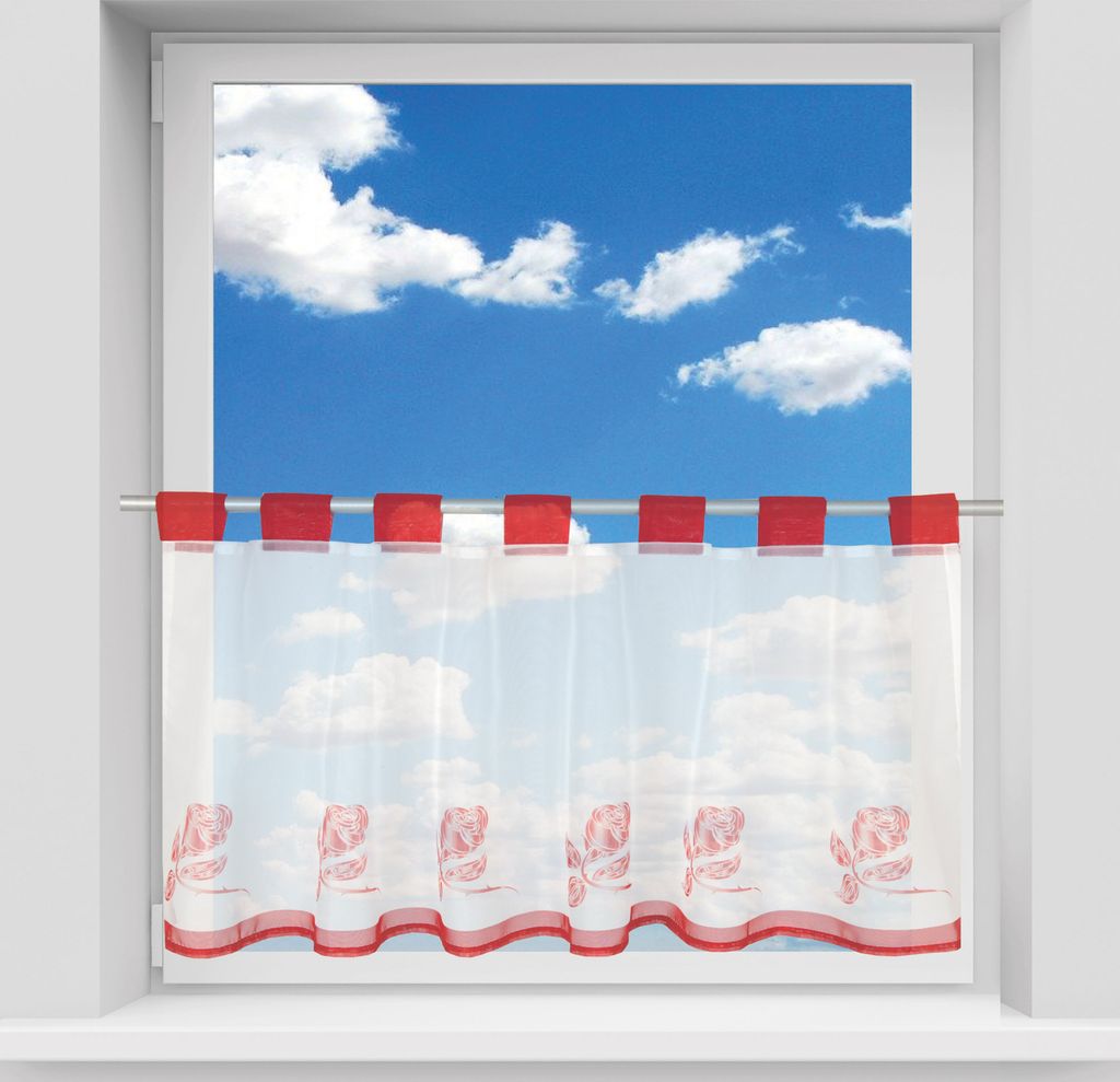 A short bistro curtain with a floral pattern hangs in a window, with a blue sky and clouds visible outside.