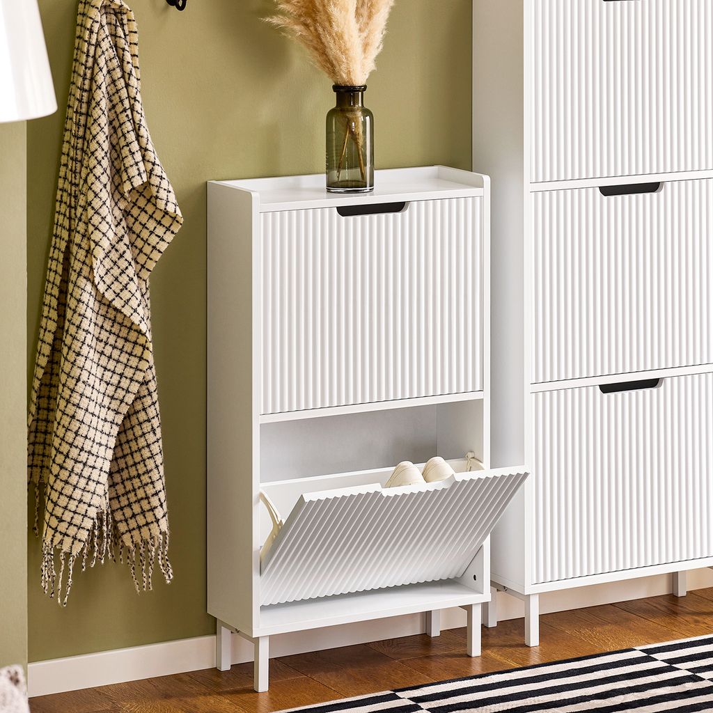 A white shoe cabinet with two flip-down compartments is shown in a room with a green wall and wooden floor.