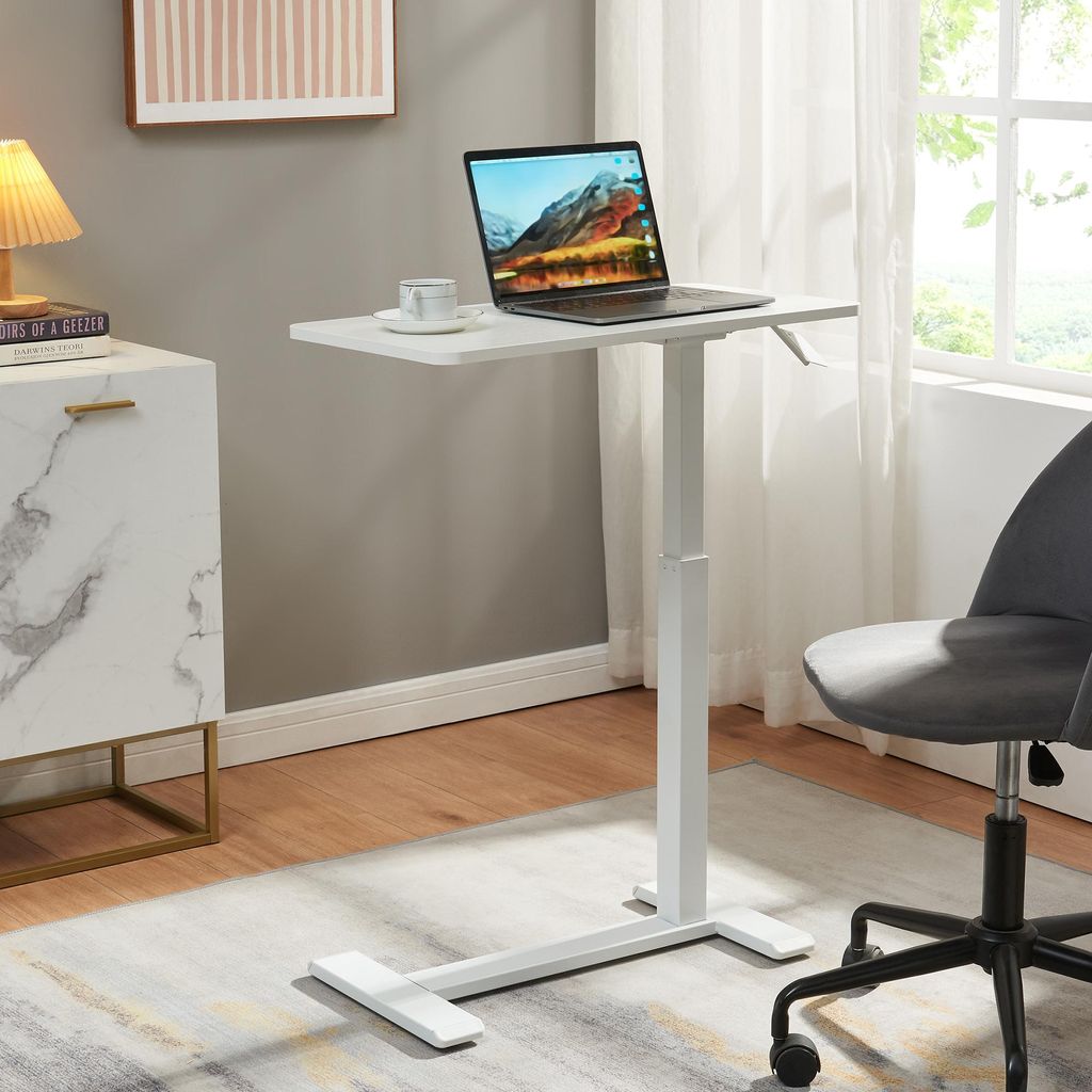 A white adjustable laptop table with a laptop, cup, and saucer on it, placed next to a marble cabinet and a grey office chair in a room with a window.