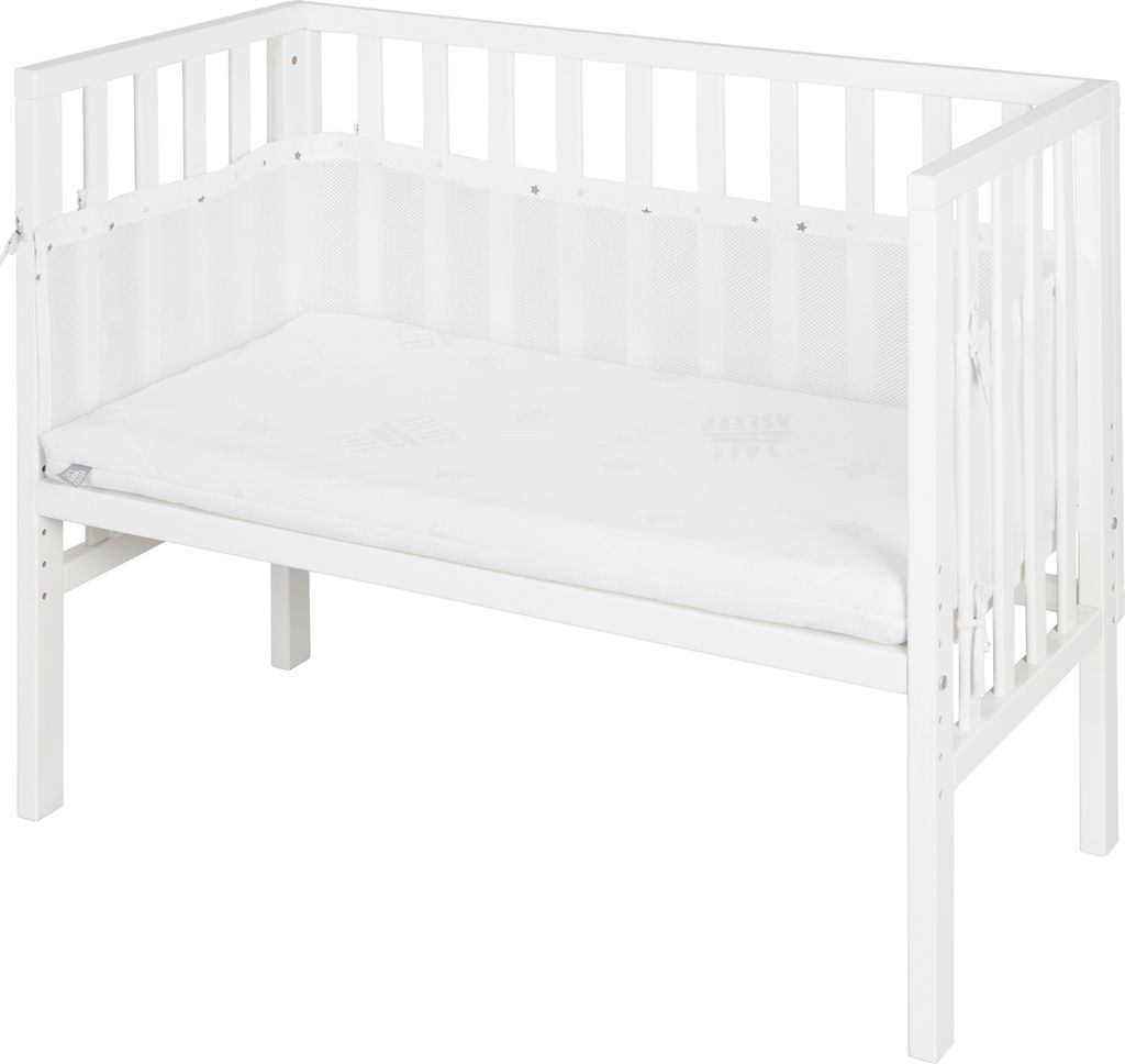 A white wooden crib with a mattress and a white mesh bumper pad.