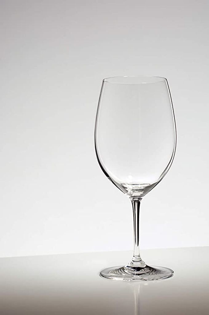 A clear glass wine glass is shown against a plain white and light gray background.