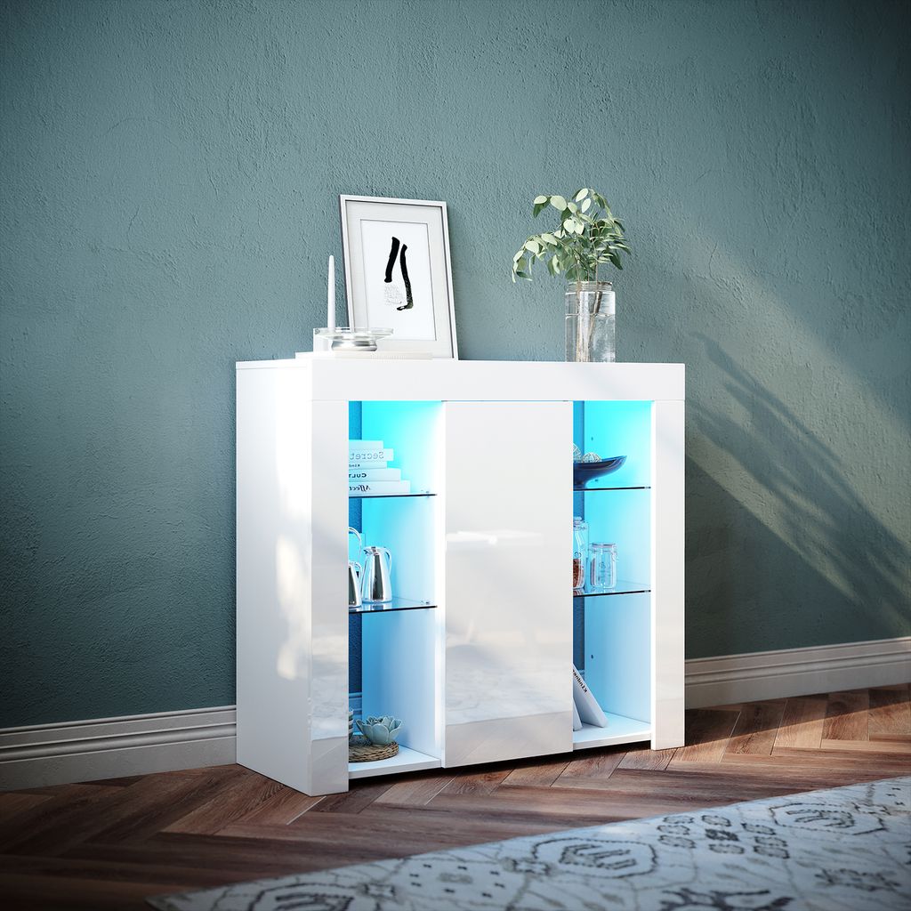 A white cabinet with glass shelves and blue LED lighting is placed in a room with a teal wall and wooden floor.