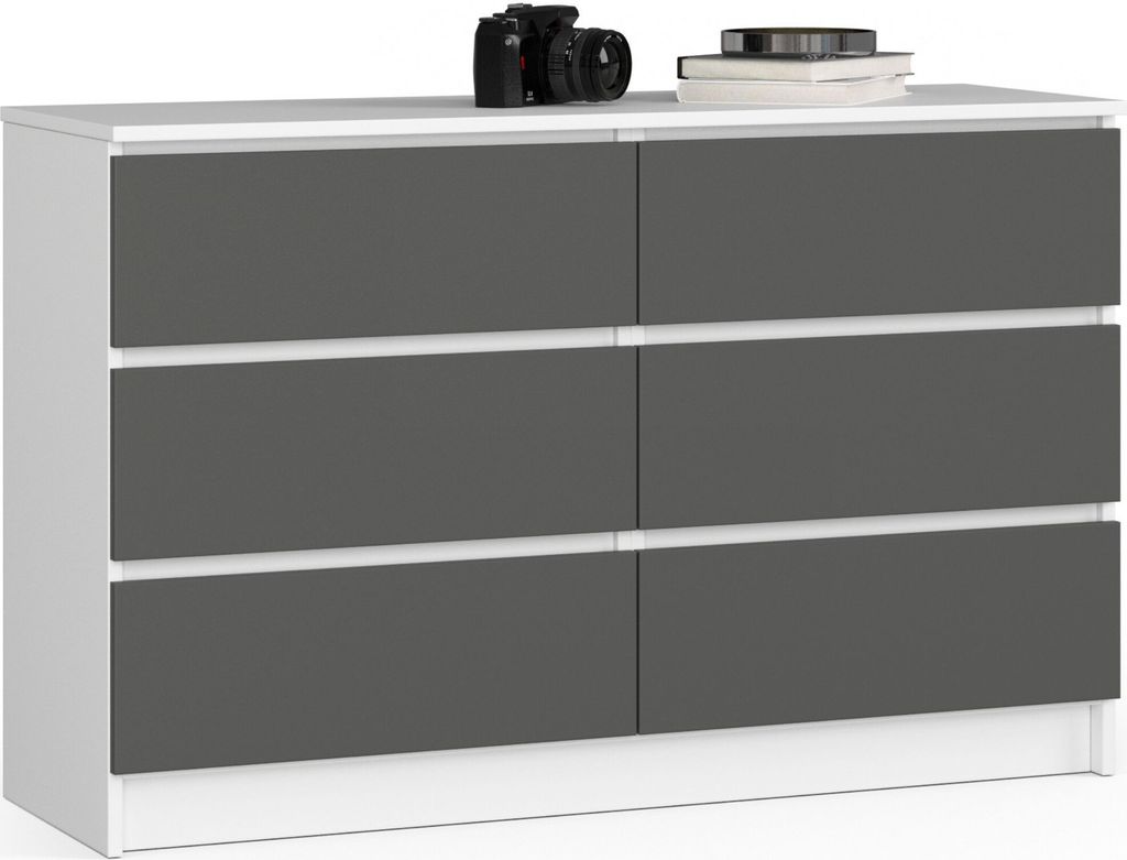 A white dresser with graphite gray drawers is displayed against a white background. A black camera and a stack of books are on top of the dresser.