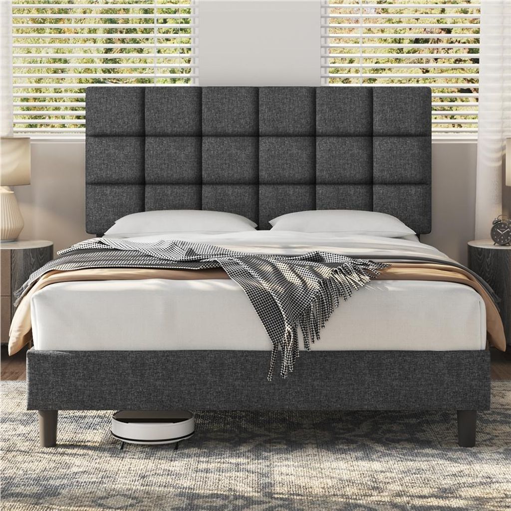 A dark gray upholstered bed frame with a tufted headboard is shown in a bedroom setting with blinds in the background.