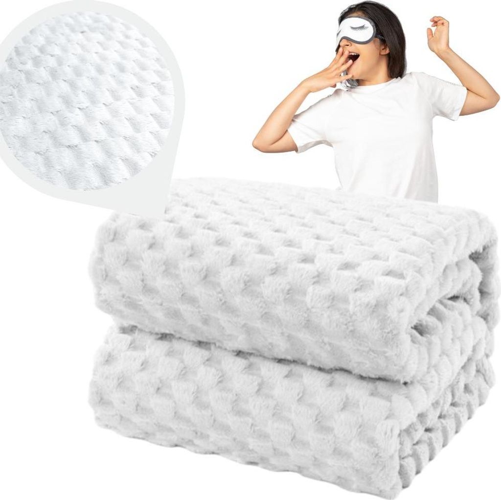 A woman wearing a sleep mask yawns, with a folded white blanket in the foreground and a close-up of the blanket's texture in the upper left corner.