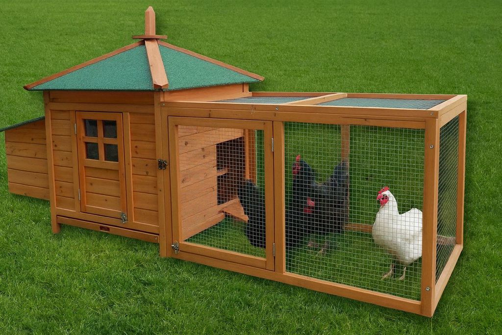 A wooden chicken coop with an attached run, set on a green lawn.
