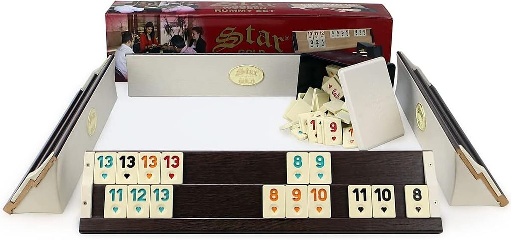 A rummy set with tiles and racks is displayed on a white surface, with its packaging in the background.