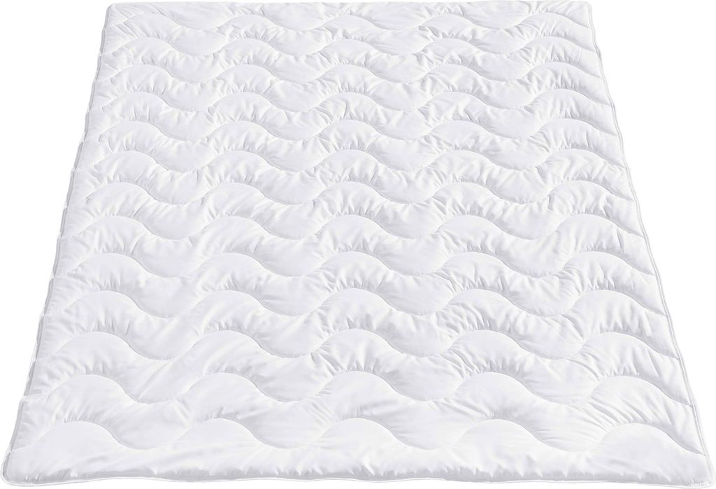 A white quilted blanket laid flat on a white background.