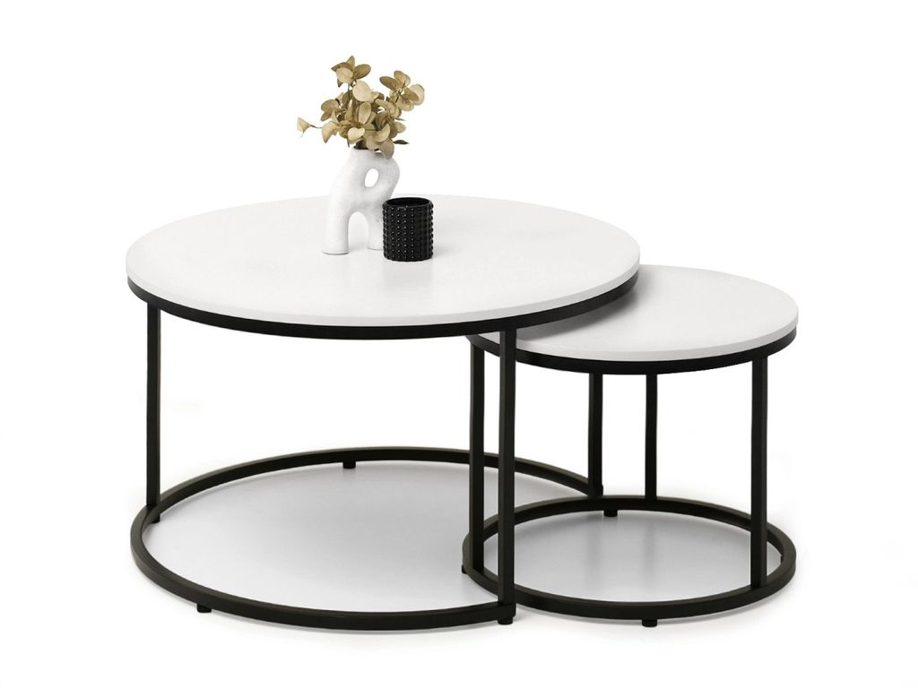 A pair of nesting round coffee tables with white tops and black metal frames, decorated with a small vase containing dried flowers and a black candle holder.