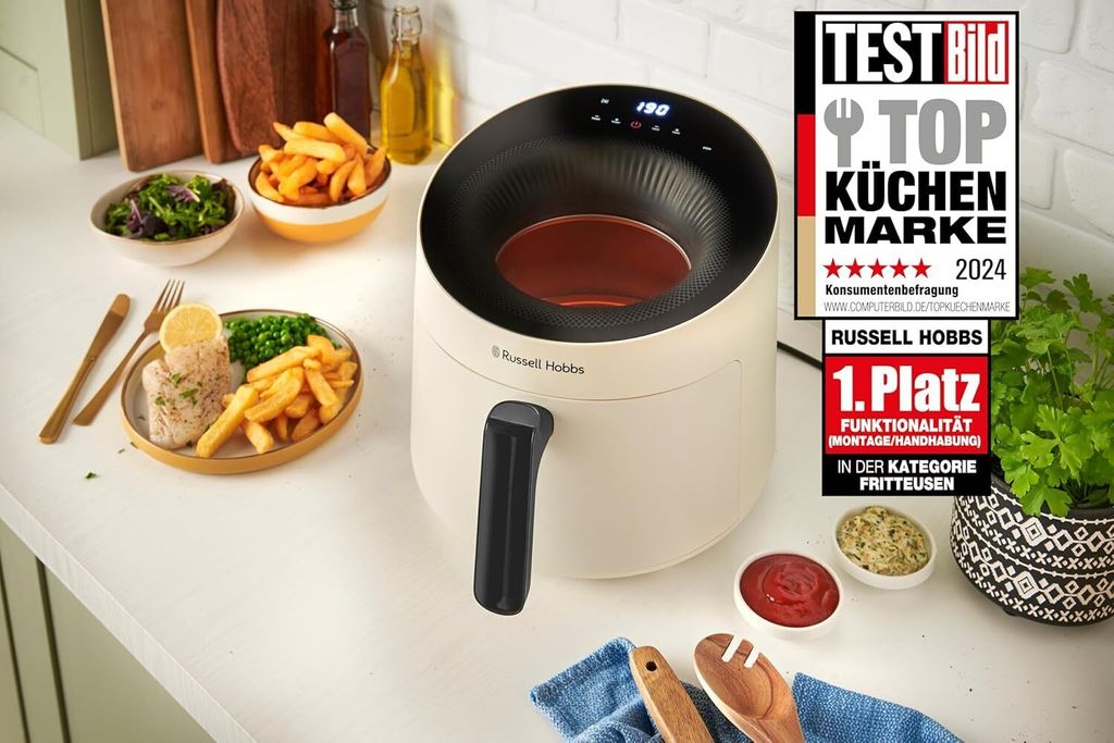 A Russell Hobbs air fryer is shown on a kitchen counter with a meal and condiments.