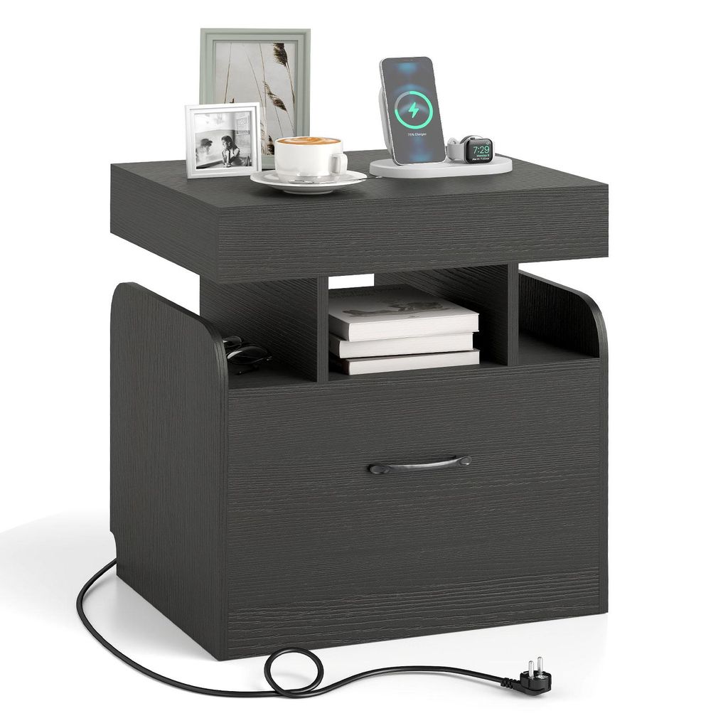 A dark gray nightstand with a drawer and open shelves, featuring a wireless charger, a cup of coffee, and picture frames on top.
