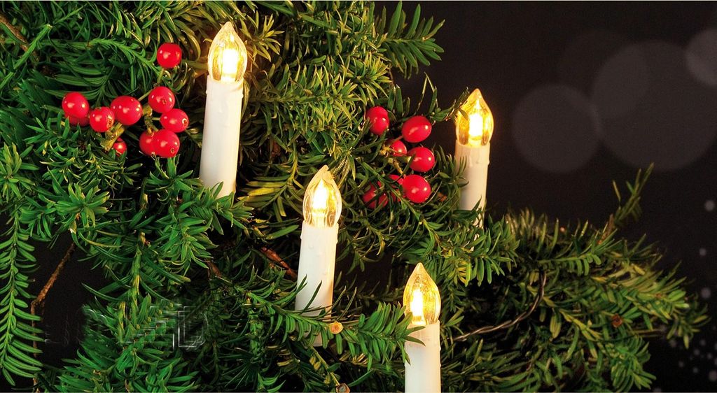 Close-up of LED candle lights and red berries on a Christmas tree.