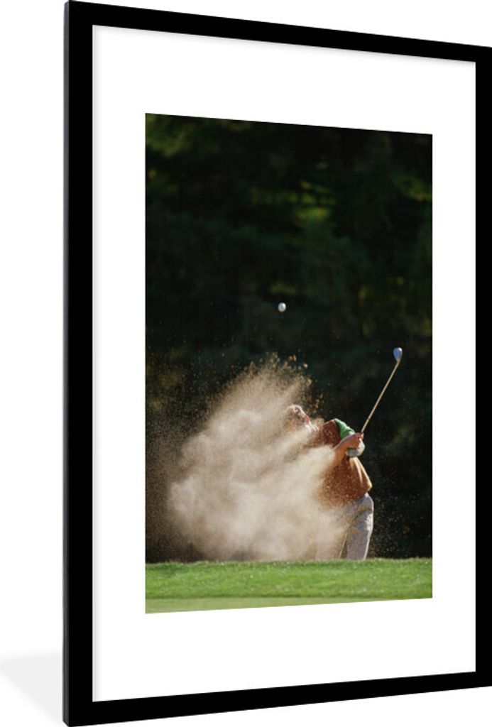 MuchoWow Gerahmtes Poster Ein männlicher Golfer schlägt den Golfball aus dem Bunker auf das Grün 60x90 cm - Poster mit Schwarzem Bilderrahmen ...