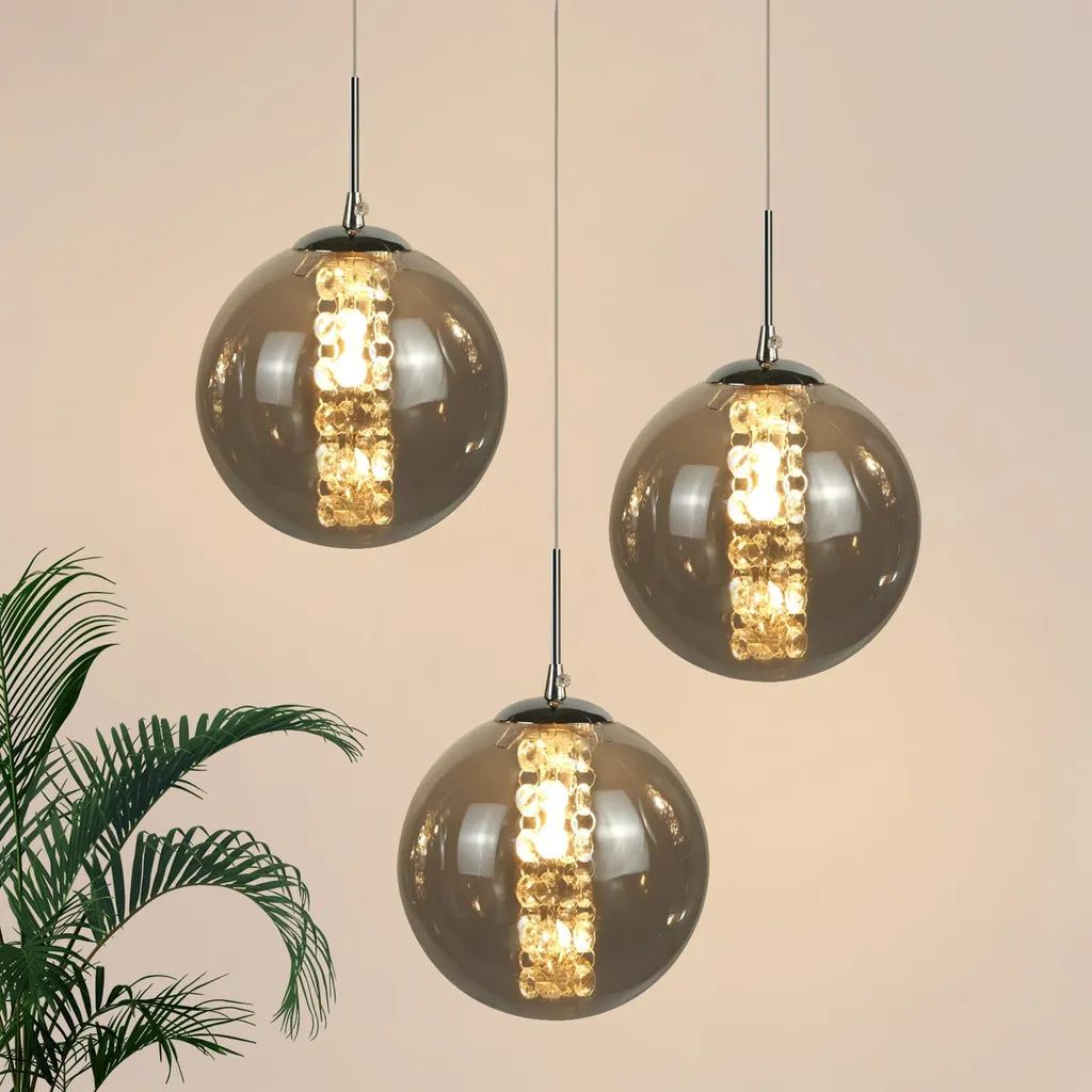 Three glass pendant lights with gold accents hanging against a light background.