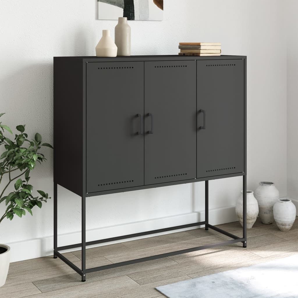 A black metal cabinet with three doors on a metal stand, placed in a room with a plant and vases.