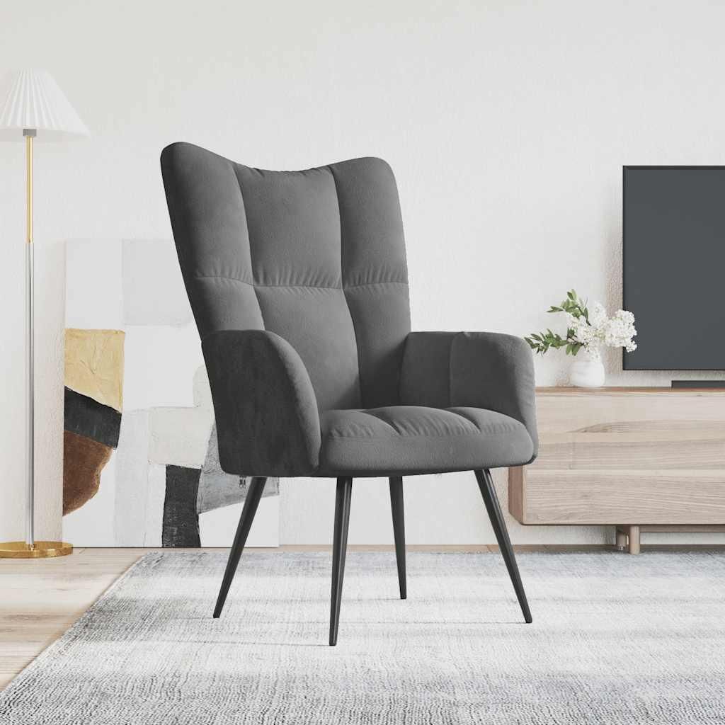 A dark gray velvet armchair is shown in a modern living room setting, with a floor lamp and a TV stand in the background.