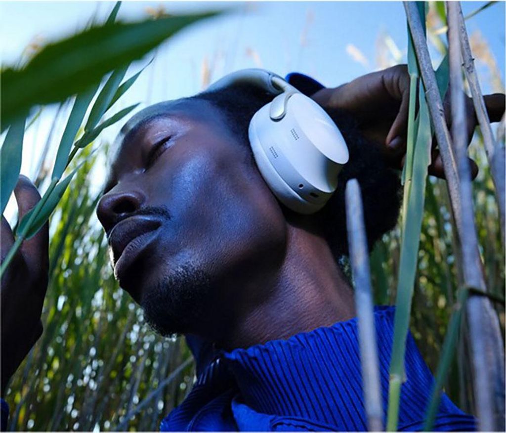 A person wearing headphones in a natural setting with reeds.