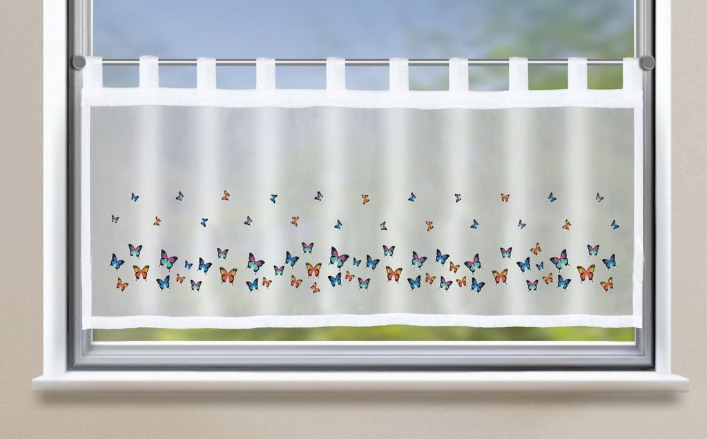 A sheer white curtain with a pattern of colorful butterflies is hung on a window.
