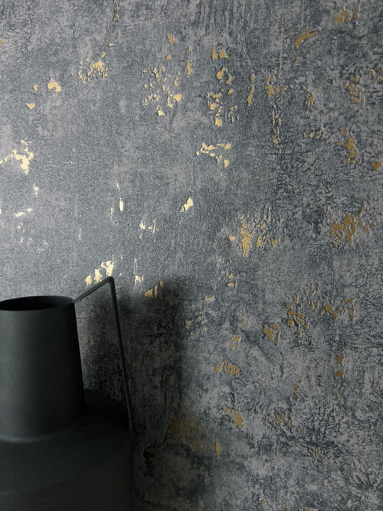 A close-up shot of a textured wall with gold accents and a black vase in the foreground.