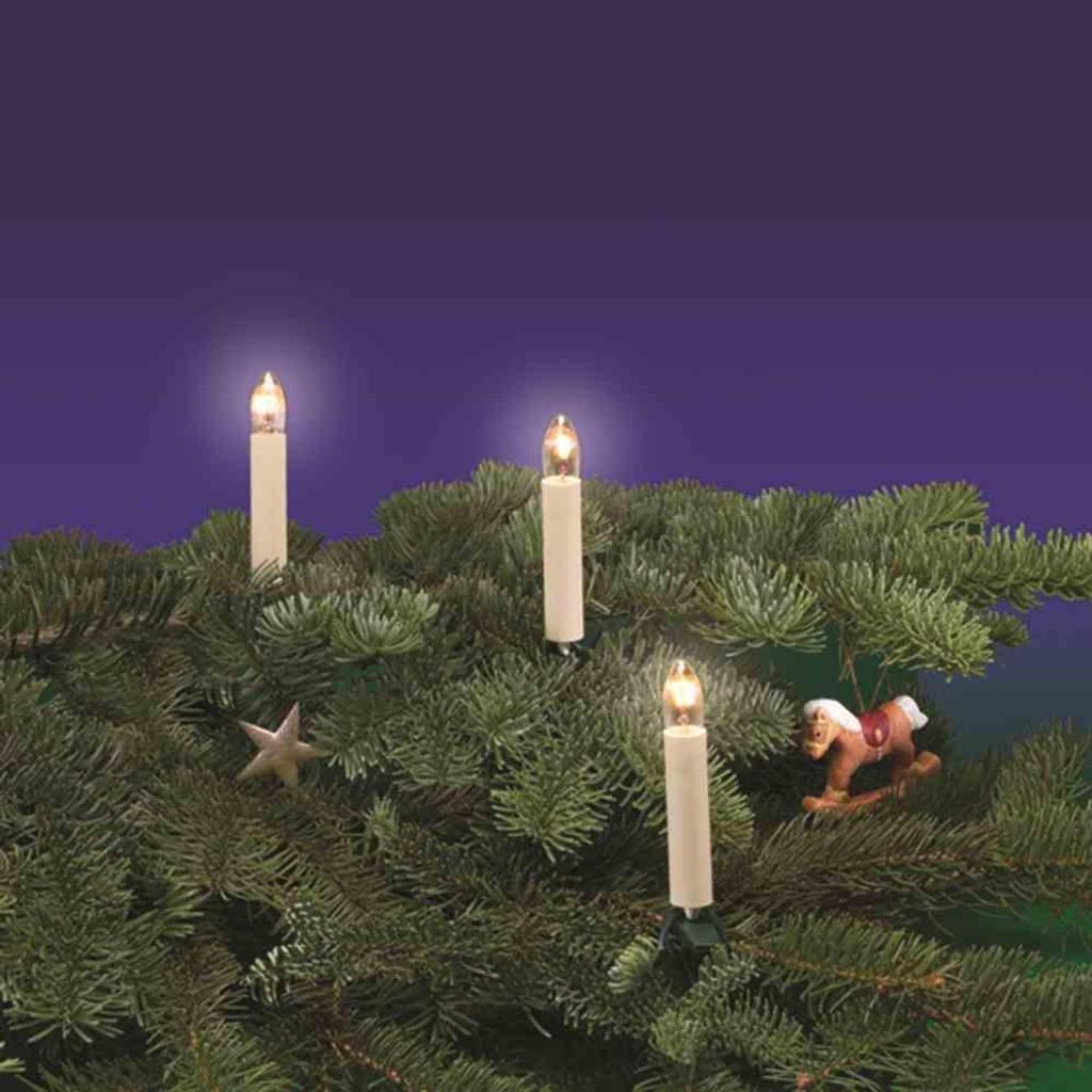 Christmas tree lights shaped like candles on a fir tree branch.