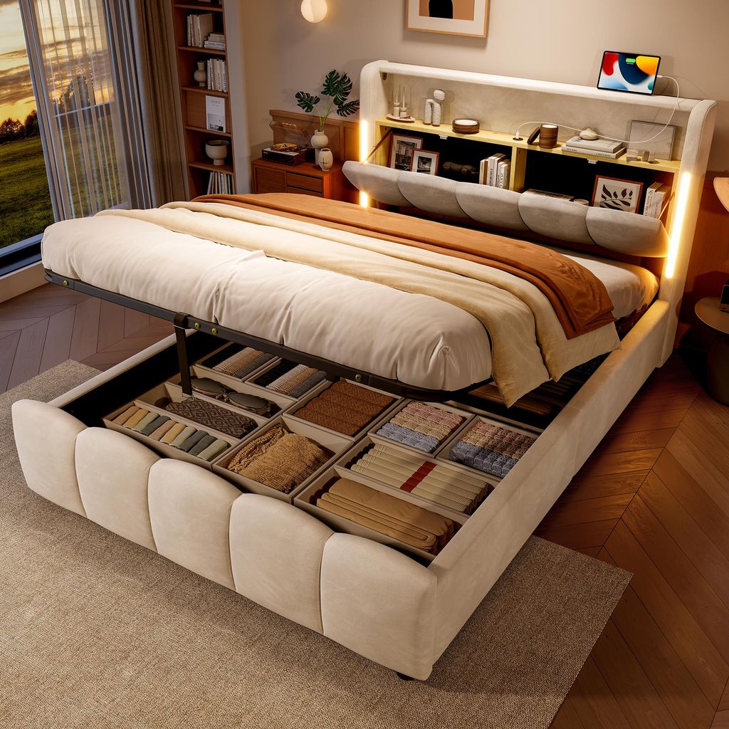 A bedroom scene with a bed that has storage compartments open, showing folded items inside. The bed has a built-in headboard with shelves and lighting.