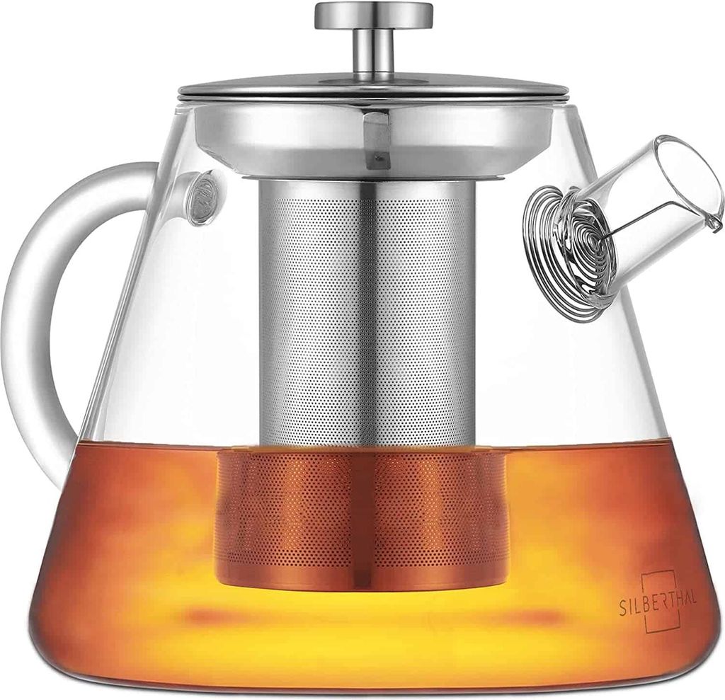 A glass teapot with a metal infuser and tea inside, presented on a white background.