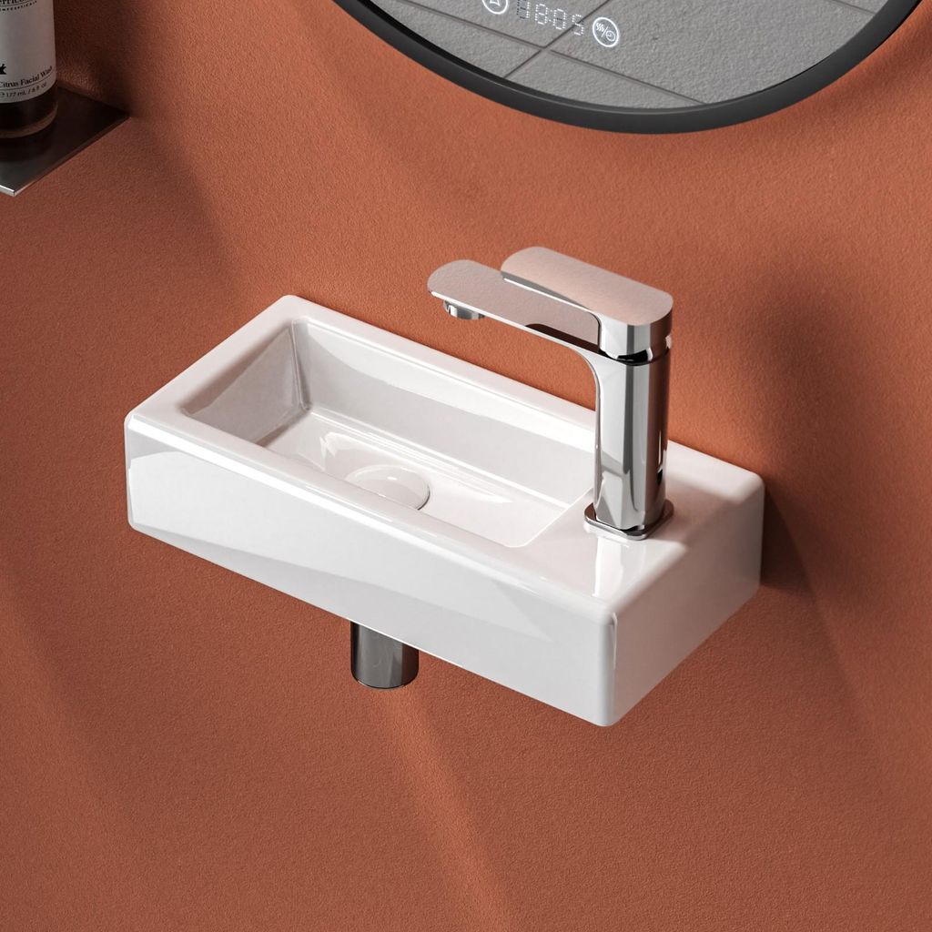 A close-up shot of a modern white ceramic sink with a chrome faucet mounted on a terracotta-colored wall.