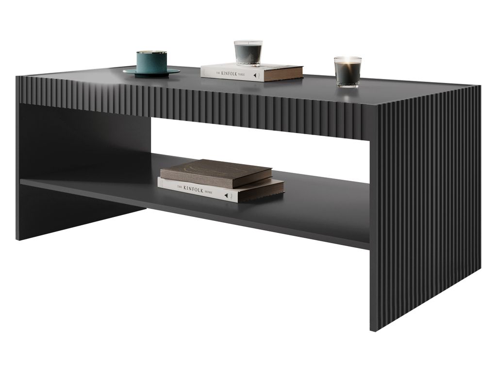 A dark grey coffee table with a fluted design on the front and sides, featuring two shelves. There are two books and two candles on the top shelf, and two books on the lower shelf.
