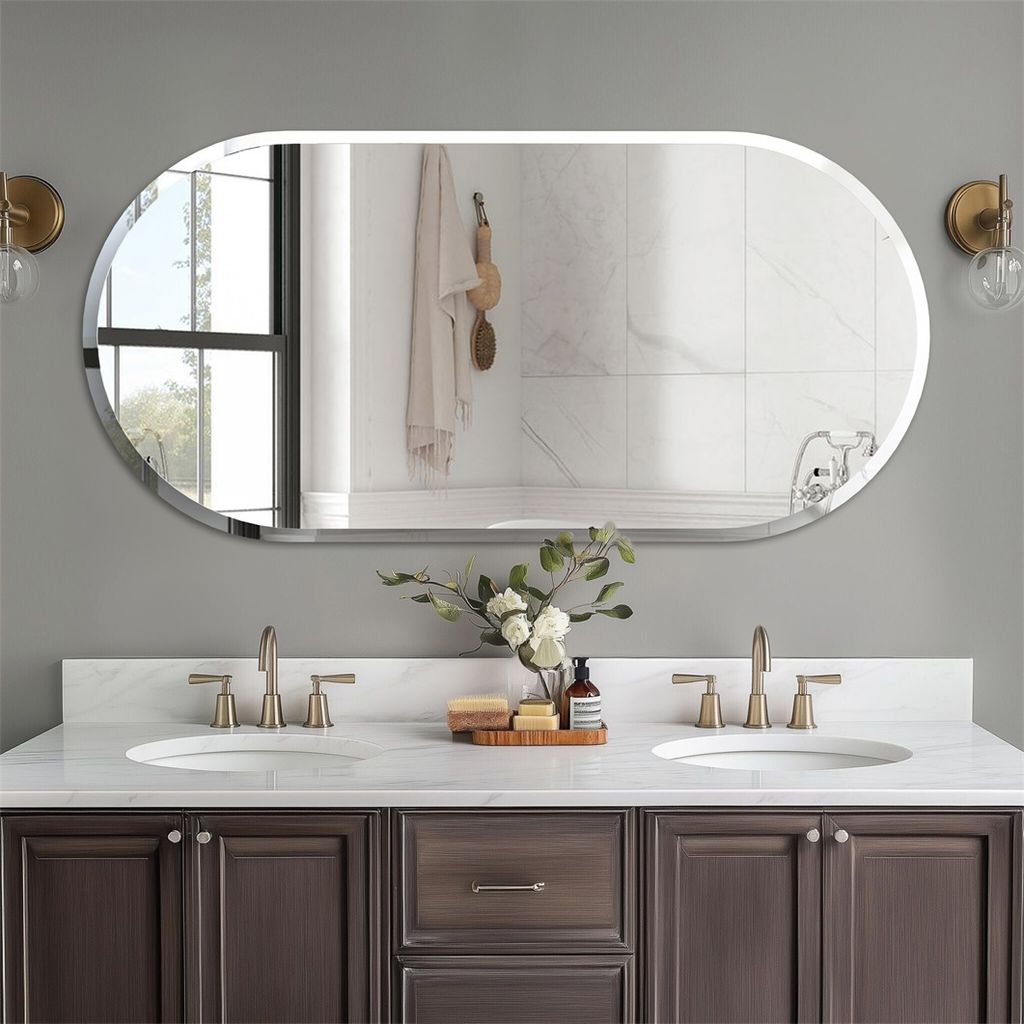 A modern bathroom vanity with a large oval mirror above it, featuring two sinks and faucets.