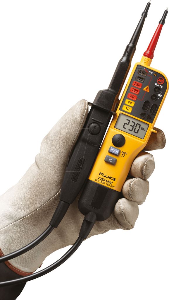 A hand wearing a protective glove holds a yellow and black digital multimeter and a black voltage tester.