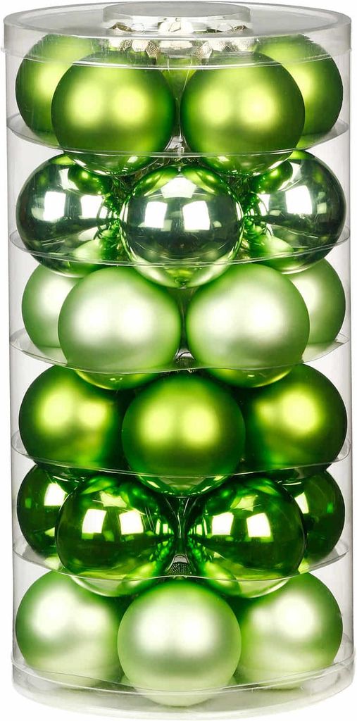 A clear, well-lit studio shot of a cylindrical container filled with green Christmas ornaments.