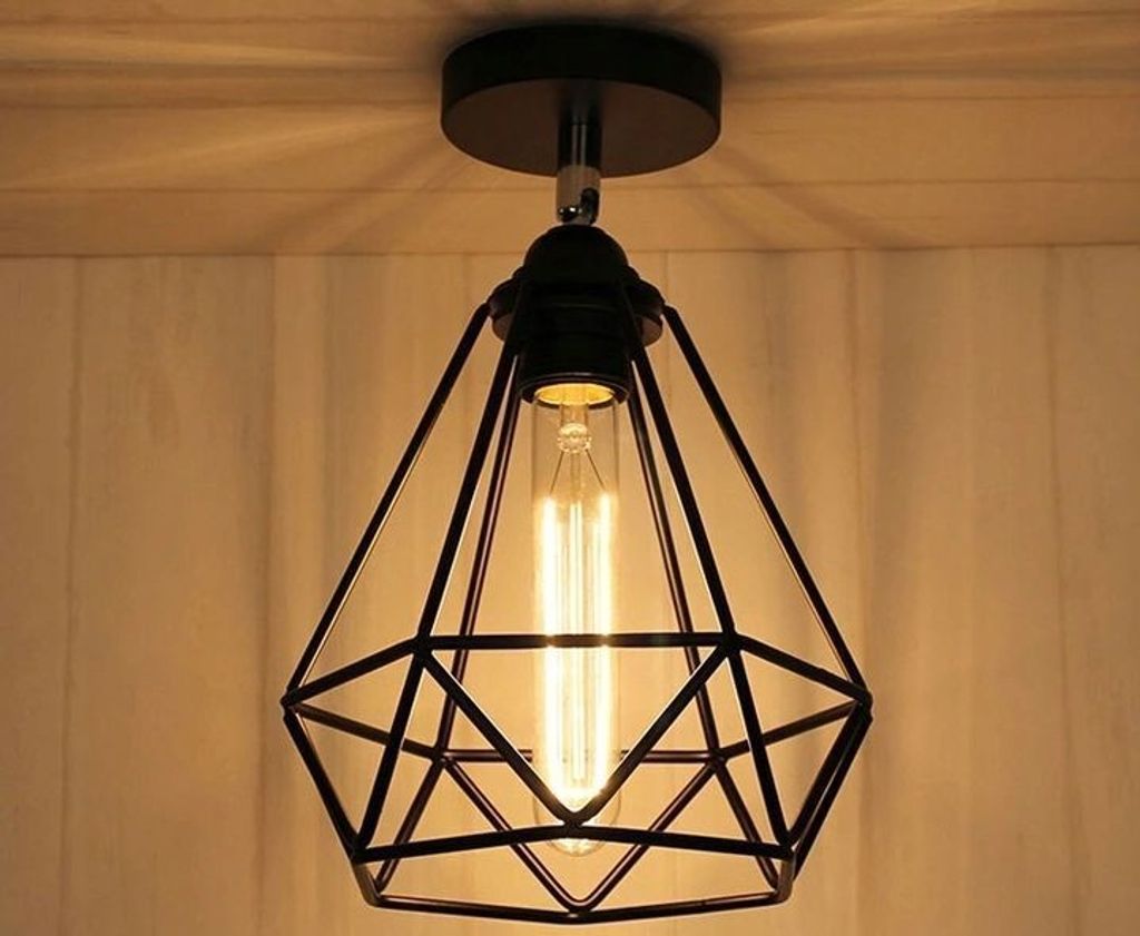 A close-up shot of a black geometric pendant light fixture with an exposed Edison bulb, mounted on a ceiling.