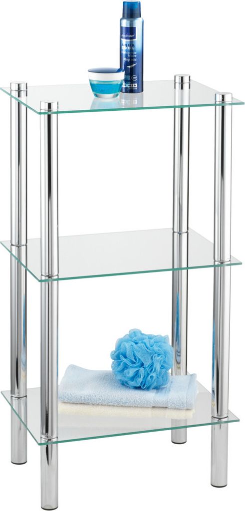 A three-tiered glass shelf unit with chrome legs, holding bathroom accessories.