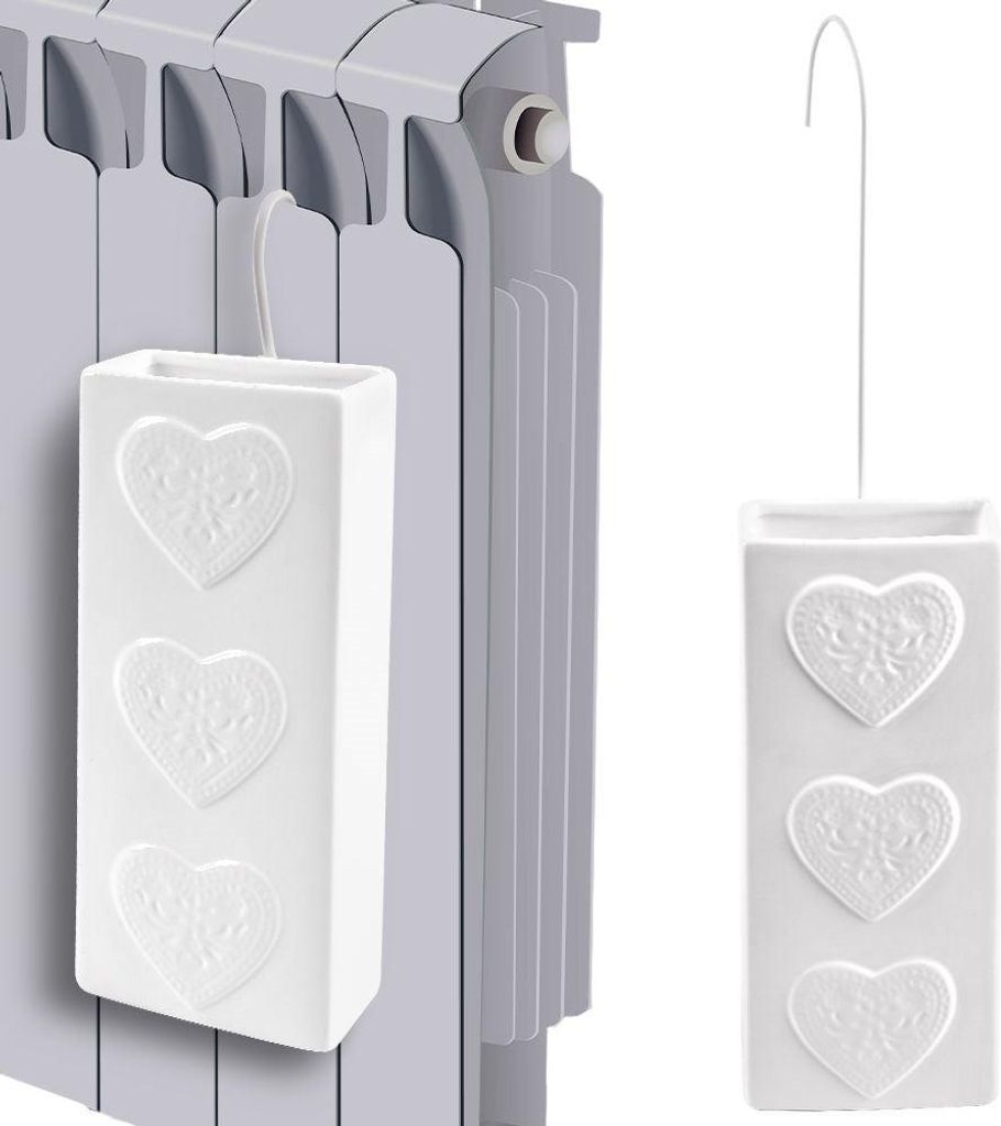 A white ceramic radiator humidifier with embossed hearts is shown hanging on a radiator.