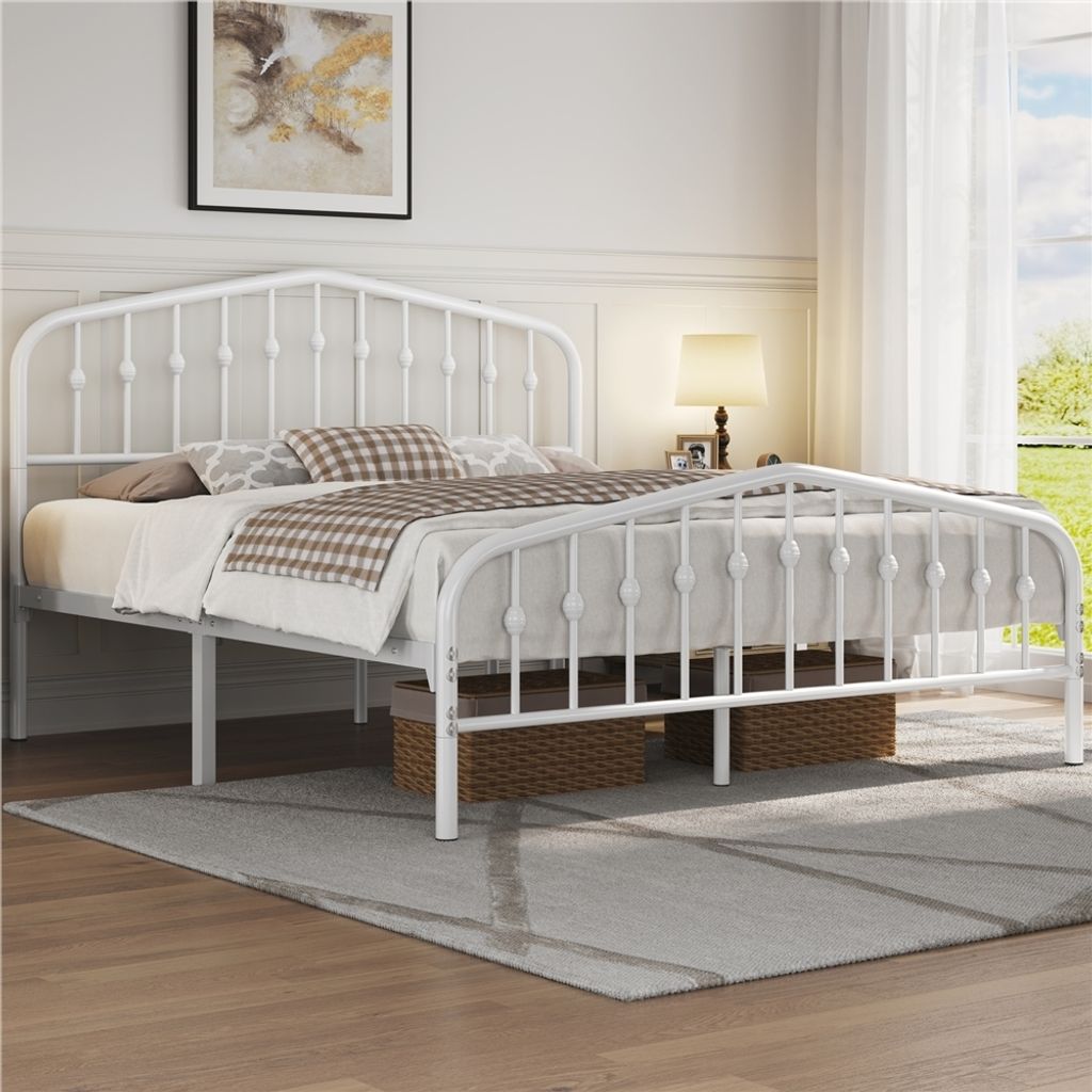 A white metal bed frame with a mattress and bedding in a bedroom setting.