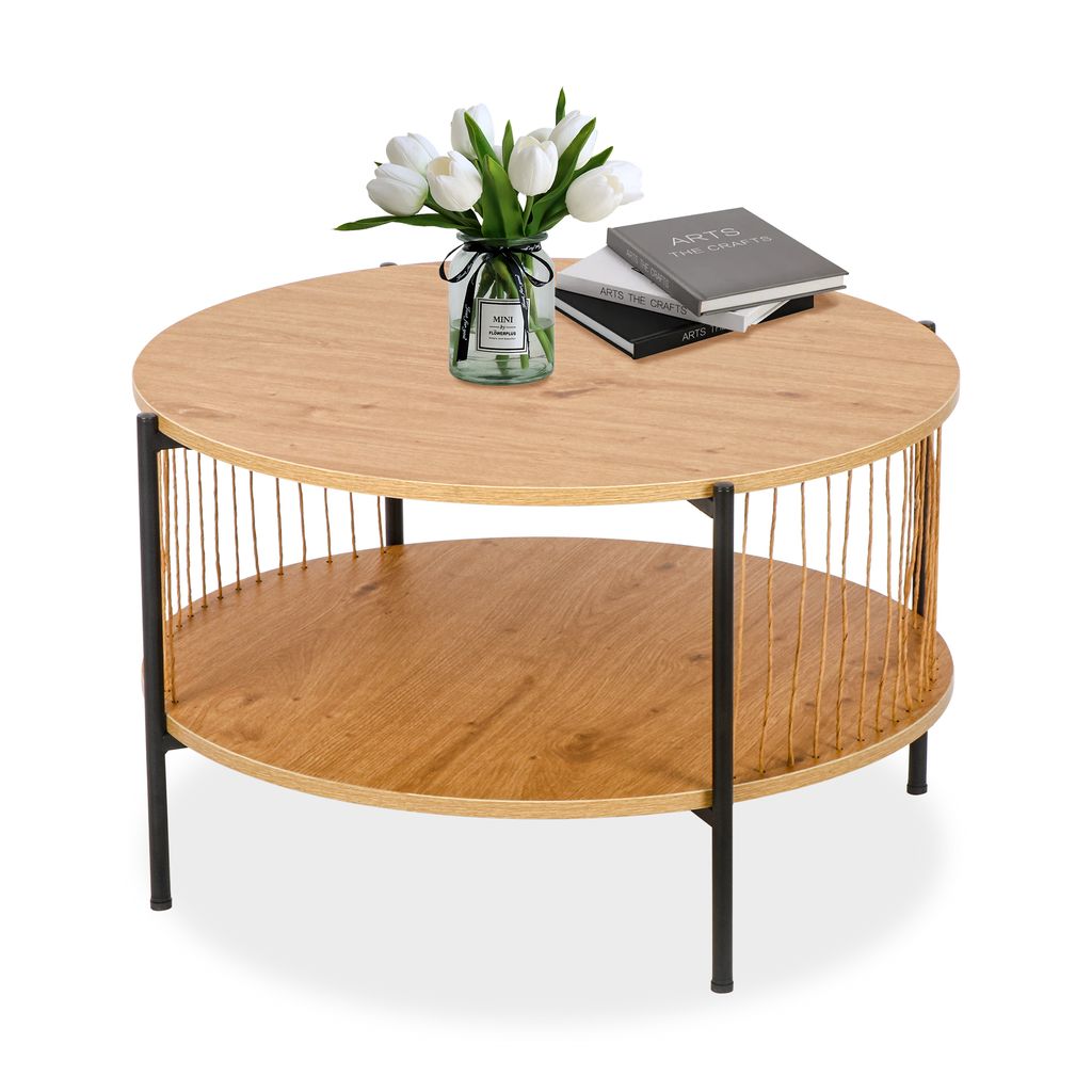 A round, two-tiered coffee table with a wood-grain finish and black metal legs, decorated with a vase of white tulips and a stack of books.