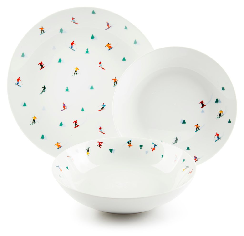 A set of white porcelain plates and bowls with a pattern of skiers and Christmas trees.