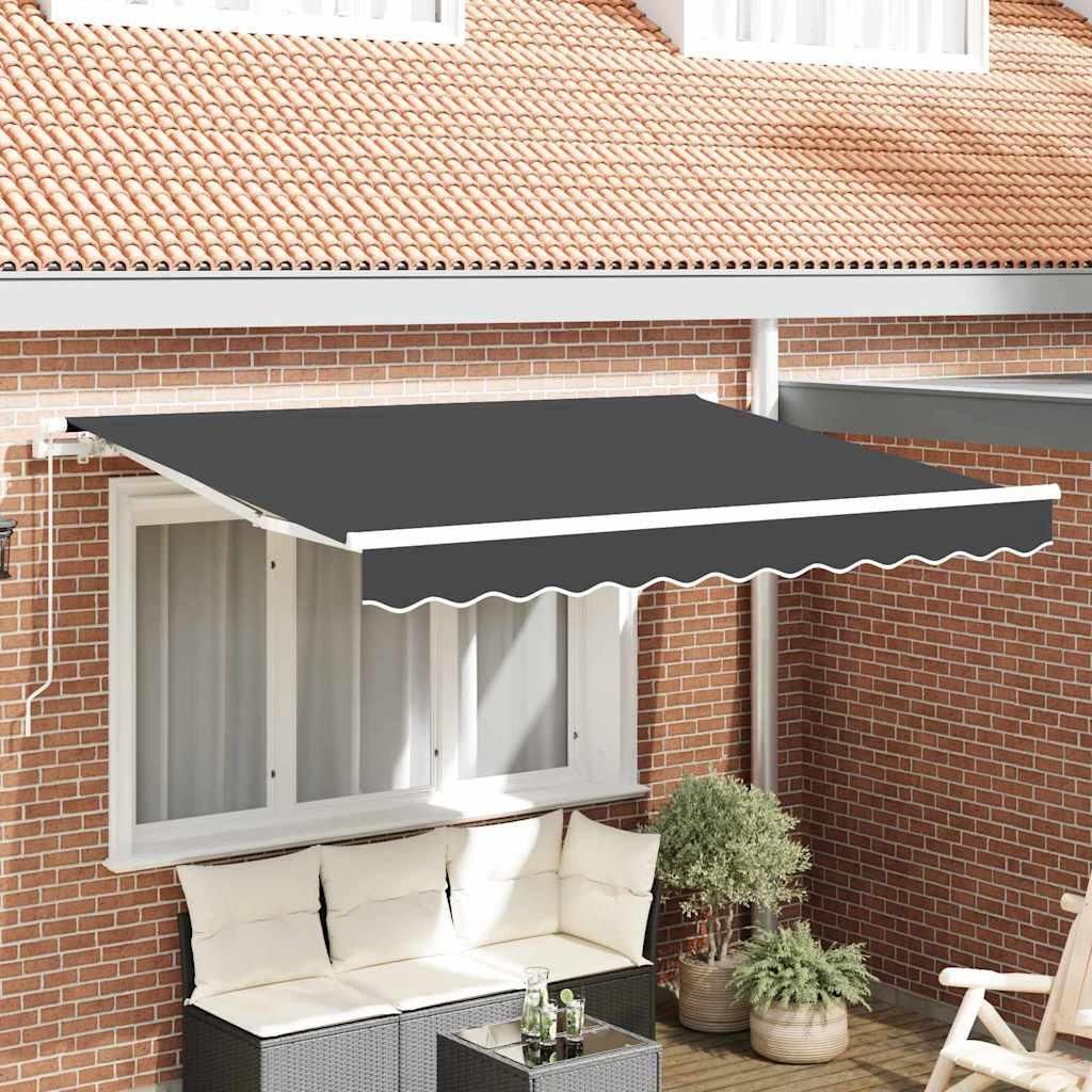 An awning is extended over a window and a seating area on a brick patio.