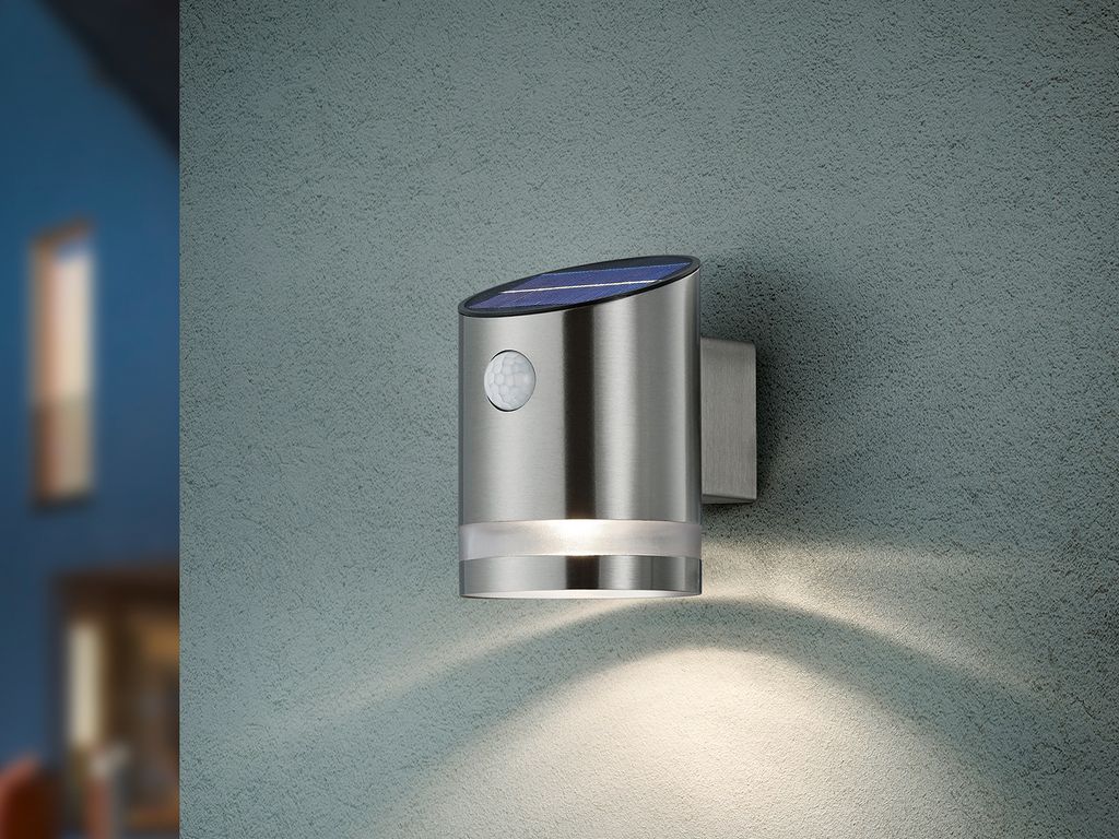 A silver solar-powered wall light is mounted on a textured gray wall.